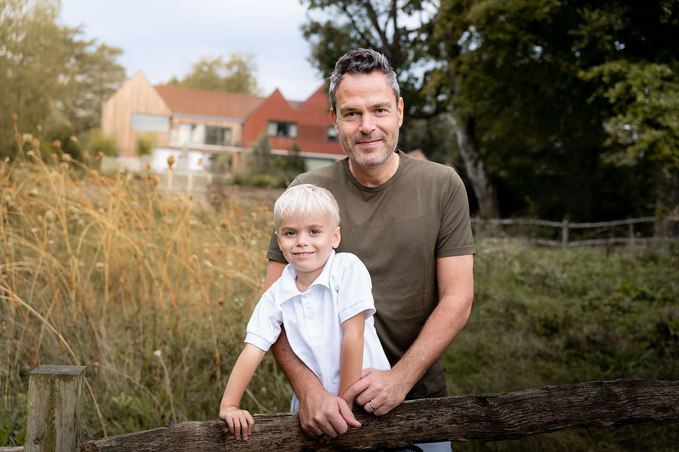 Father stood with his young son in a meadow during a relaxed outdoor family photoshoot.
