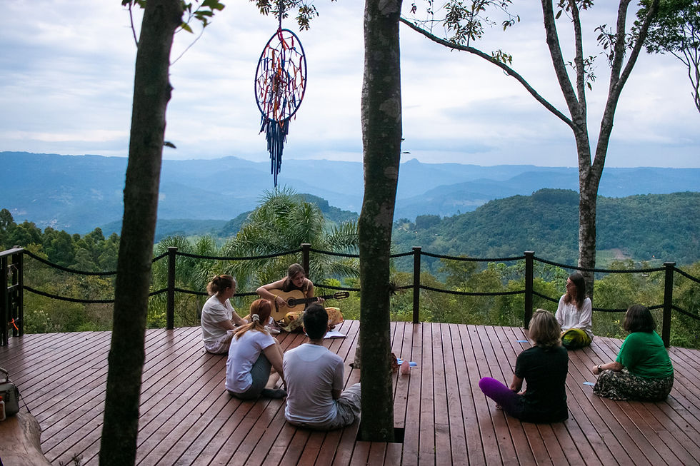 Pessoas sentadas e ouvindo outra tocar violão