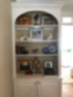 styled shelves with grass cloth wallpaper in back