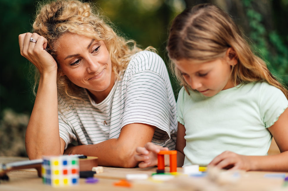 Mother supporting child as she plays with blocks