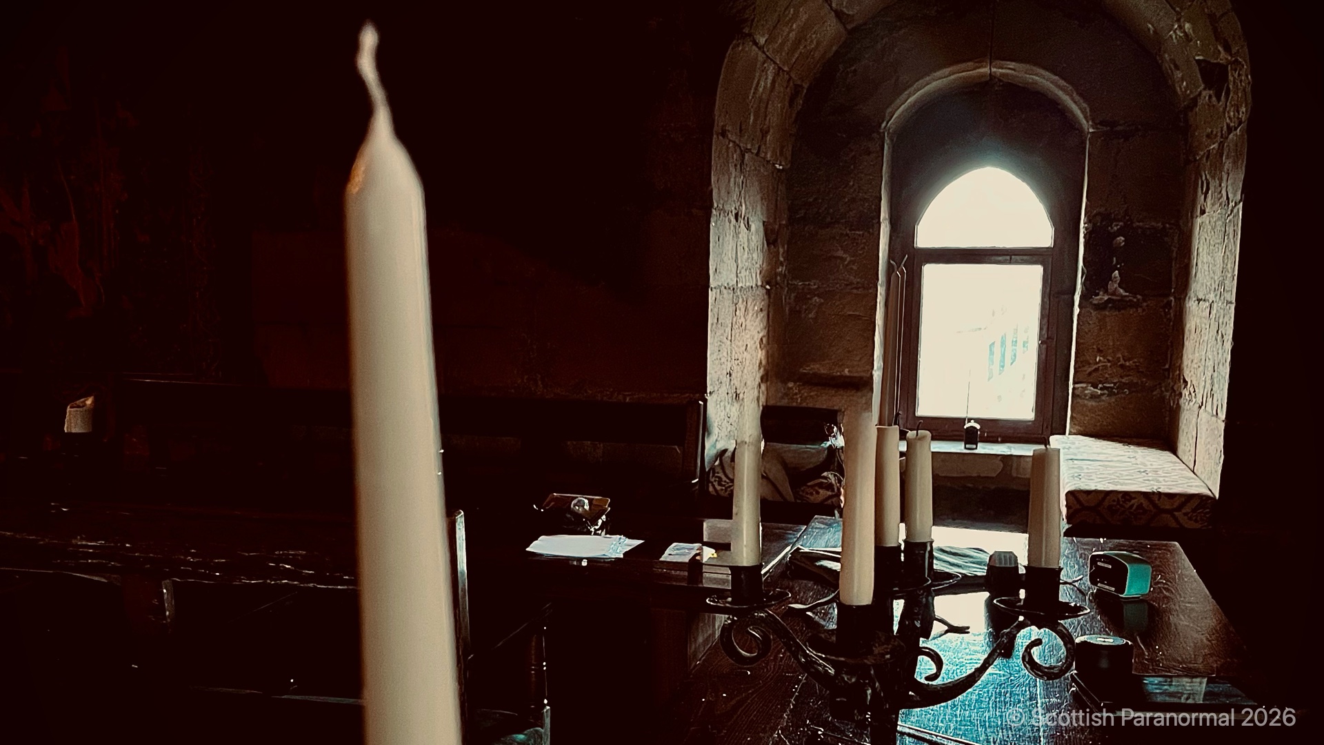 Candlesticks and investigation equipment beside an arched window at Balgonie Castle.