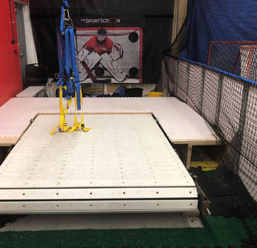 Indoor hockey training setup with synthetic ice and harness