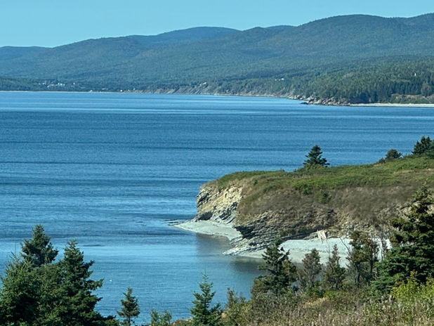 Ocean coastline with a rocky point and green hills
