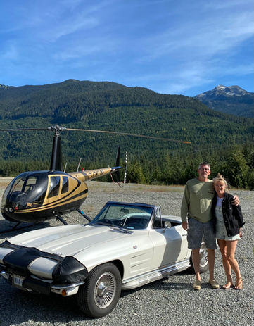 Couple with classic car and helicopter in mountains