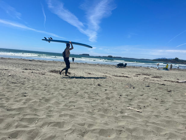 Man carrying a surfboard on a sunny beach
