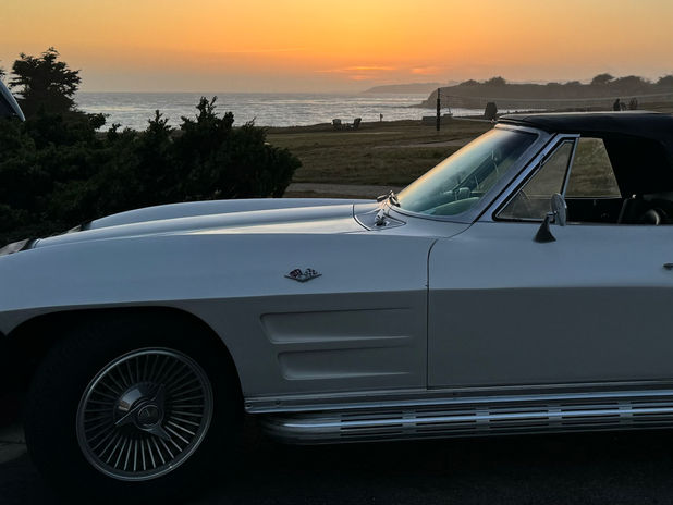 White classic car by the sea at sunset