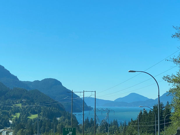 Scenic highway view of mountains, lake, and exit sign