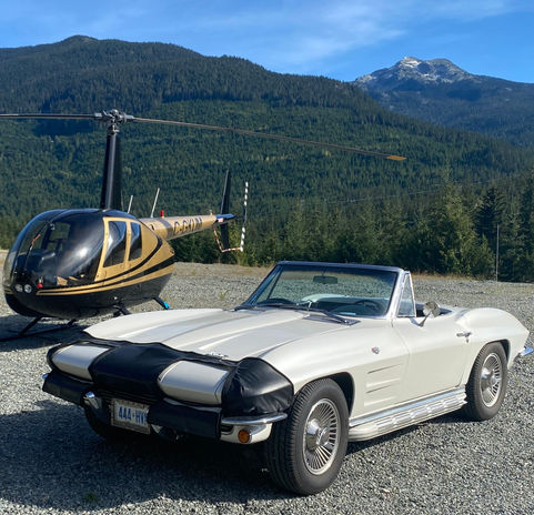 White classic convertible and helicopter in mountains