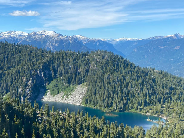Mountain lake nestled in evergreen forest with snowy peaks