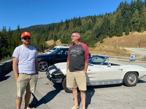 Two men and a classic car on a scenic mountain road
