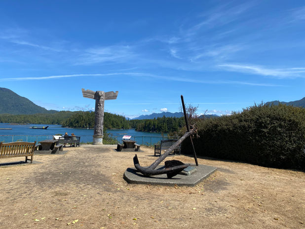 Sculpted anchor and totem pole by a coastal bay