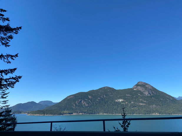 Green mountains rise above blue water under a clear sky