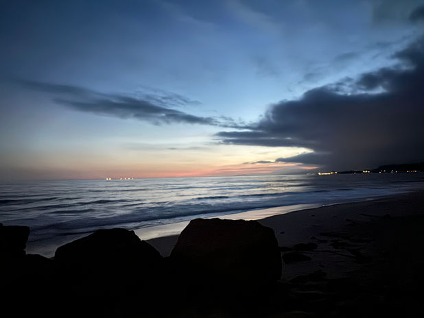 Dusk at the beach with waves and rocks
