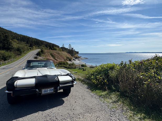 Classic car parked on a scenic coastal road.