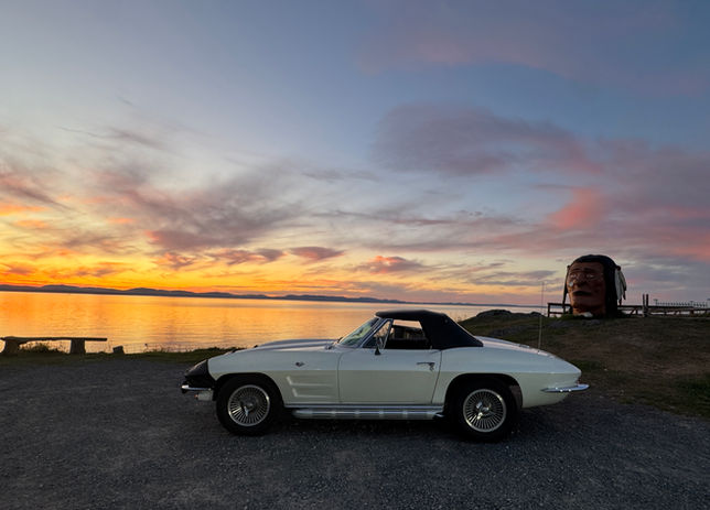 White classic convertible by water at sunset