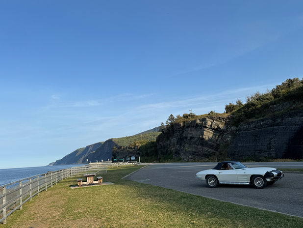 White convertible car on scenic coastal road with cliffs