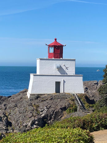 White lighthouse with red top on a rocky cliff by the sea