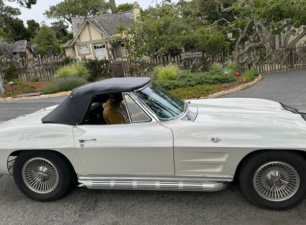 White classic convertible car with black top, person driving