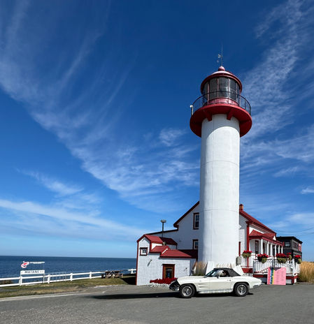 White lighthouse with red roof, classic car, ocean