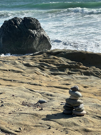 Rock cairn on rocky coast with ocean waves