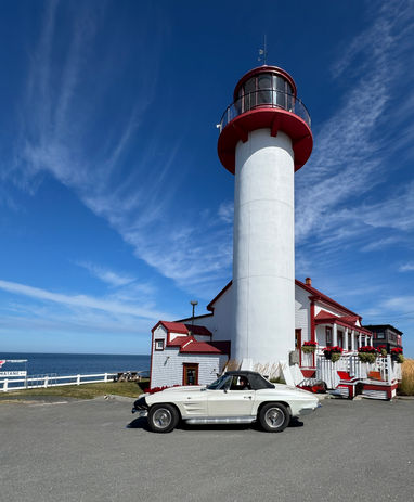 Classic white car by a lighthouse on the coast