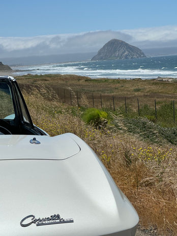 White convertible parked overlooking rocky coast and ocean