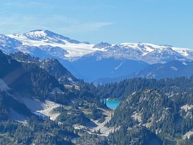 Snowy mountain landscape with a turquoise lake and pine trees