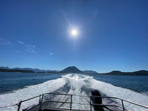 Boat wake on water with islands under sunny sky