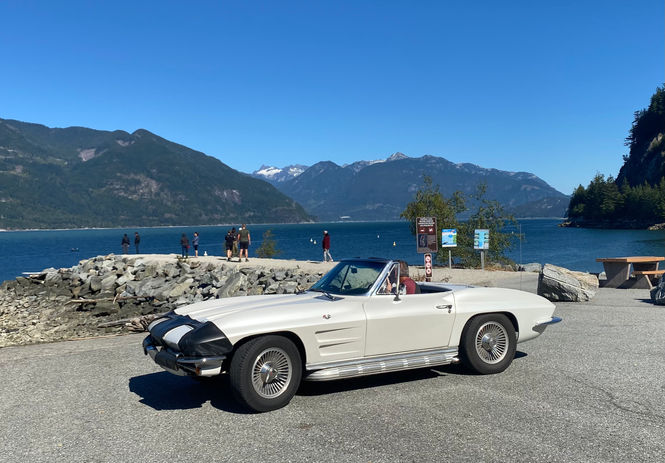 Classic white Corvette by lake and mountains