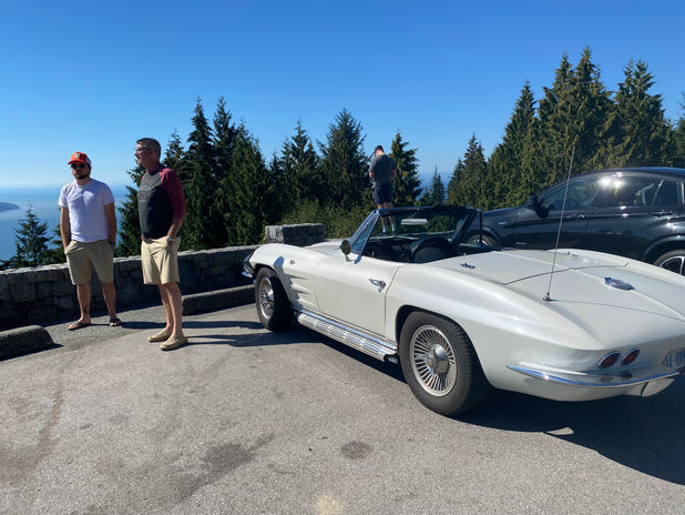 Men and white classic convertible at a scenic mountain overlook