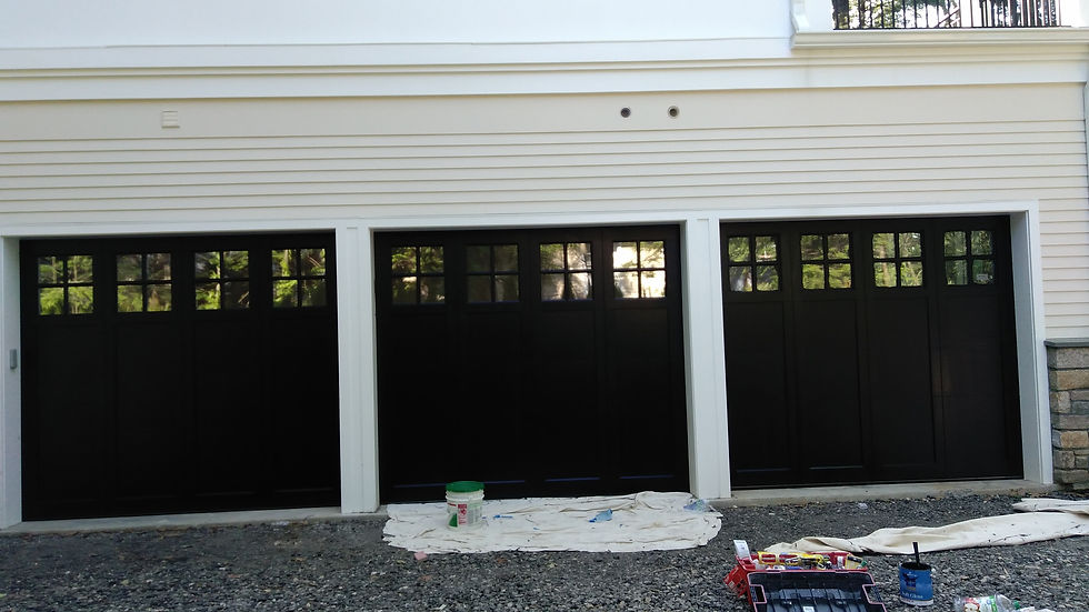 Three black garage doors with windows on a house