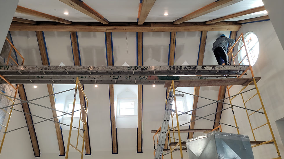 Worker on scaffolding renovating a room with exposed beams