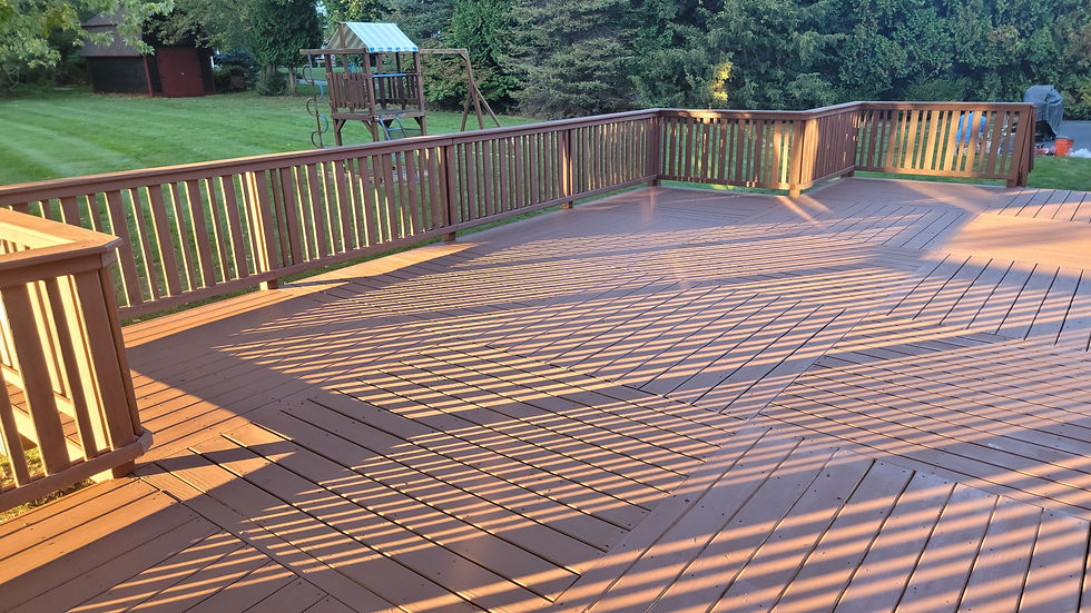 Spacious wooden deck with railings overlooking a green lawn