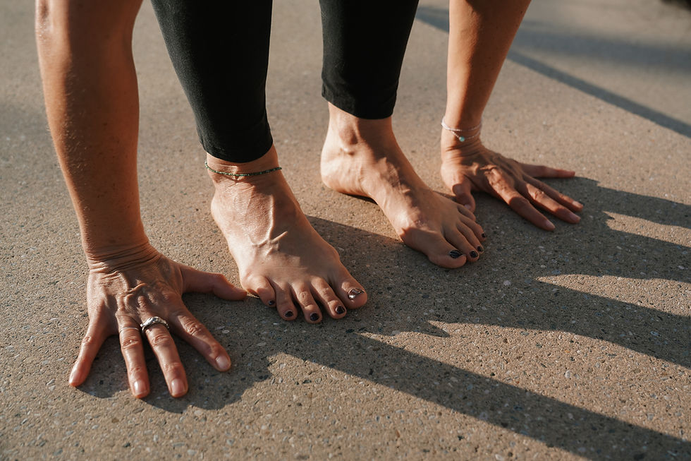 Hände und Füße einer Frau auf dem Boden aufgestellt wie in einer Yogahaltung Uttanasana