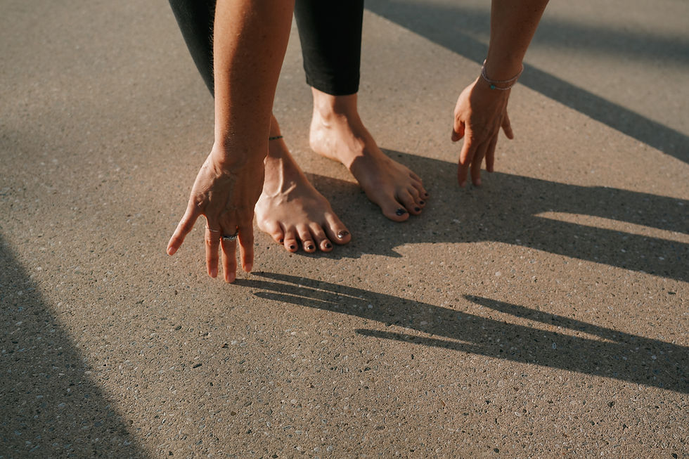 Füße einer Frau barfuß auf dem Boden daneben sind ihre Hände auf die Fingerspitzen gestellt wie im Yoga