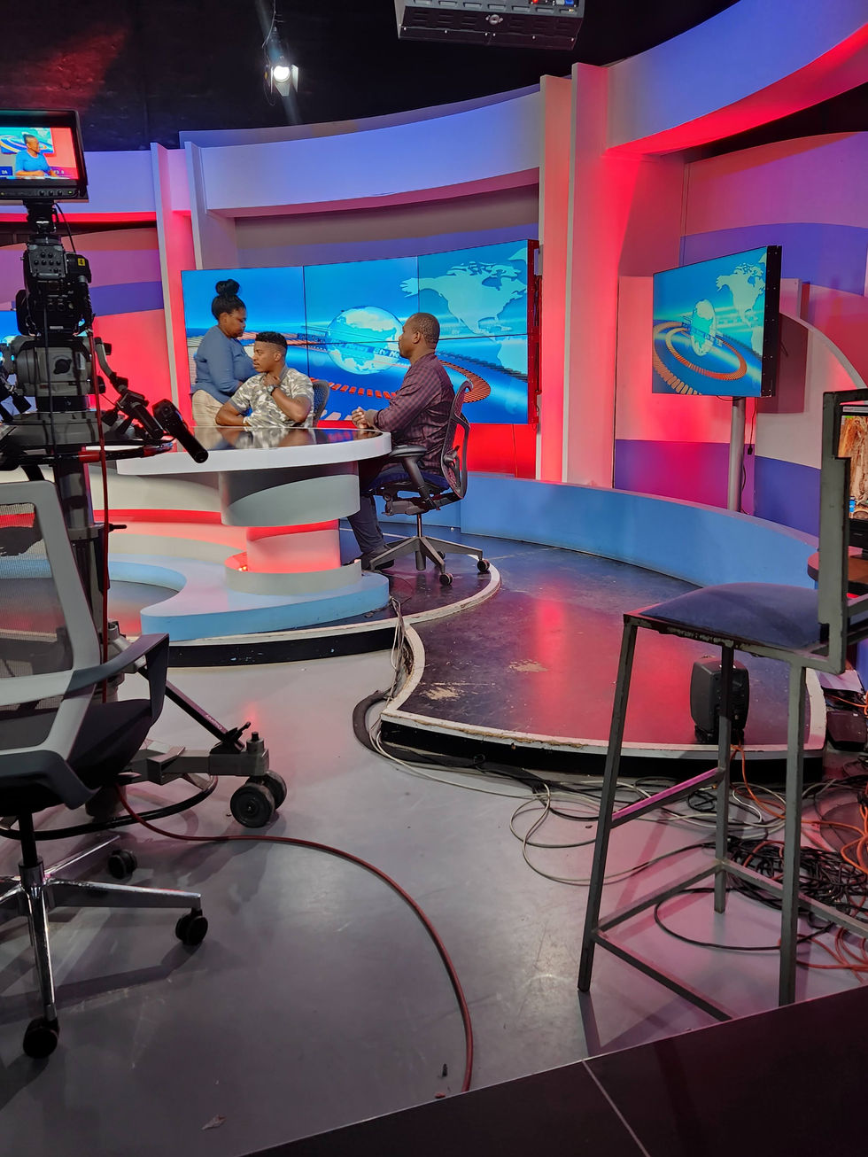 a man sits at a desk in front of a screen that says news
