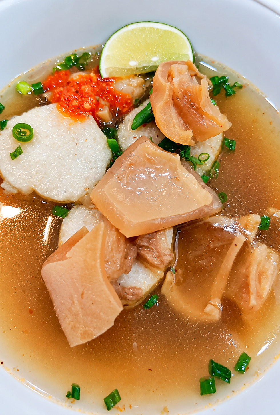 Lontong lembut dengan kikil sapi empuk dalam kuah gurih kaya rempah, disajikan hangat dengan taburan bawang goreng dan seledri.