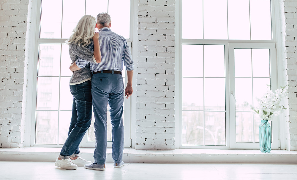 Older man and woman looking out large windows