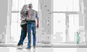 Older man and woman looking out large windows
