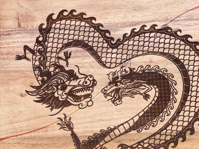 Image: A rectangular wooden cutting board laser-engraved with an illustration of two Chinese zodiac dragons forming the shape of a heart

Text: John & Meg Wen, 2-2-2019
