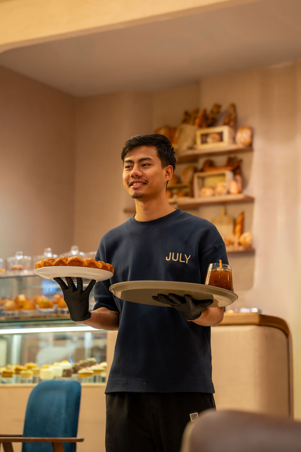 Person holding trays with pastries and drinks.
