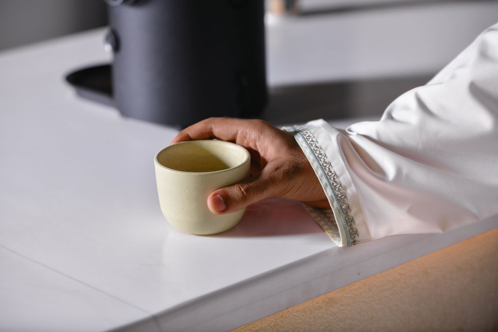 Hand holding a small cup on a table.