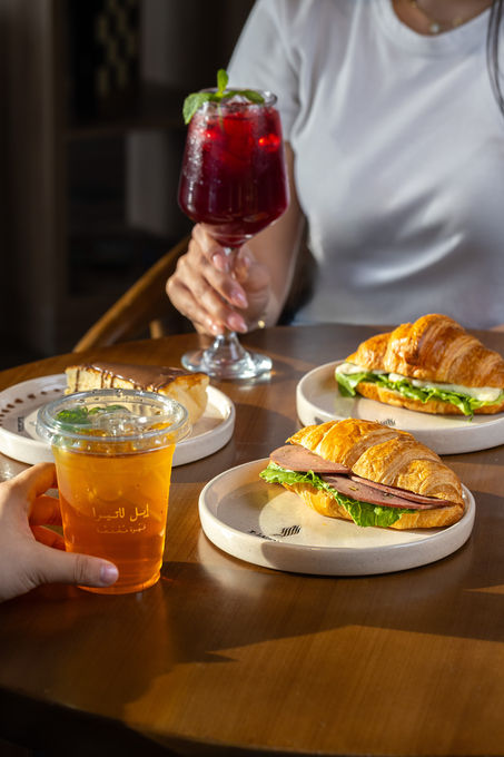 Two people enjoying croissants and drinks at a table.