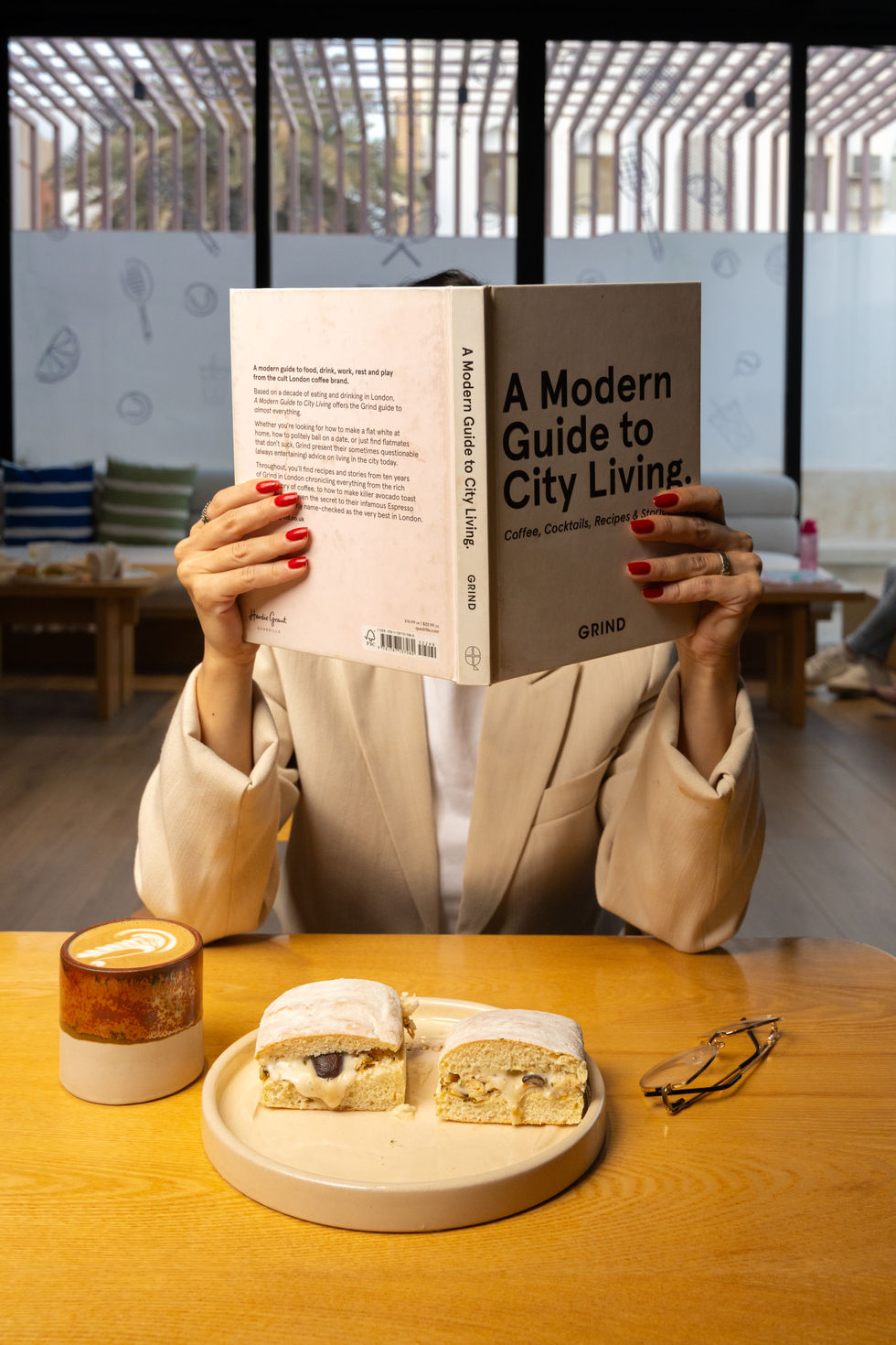 Person reading book in a cafe with coffee.
