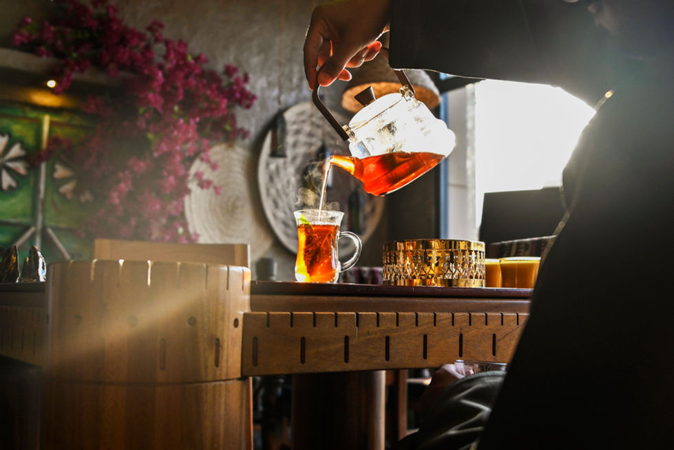Pouring tea into a glass on a wooden table.