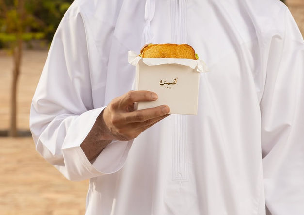 Person holding a pastry in a white container.