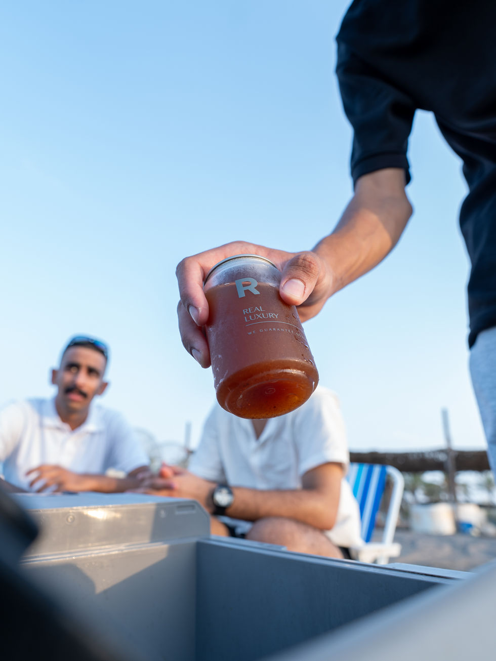 Person handing drink to seated individuals outdoors.