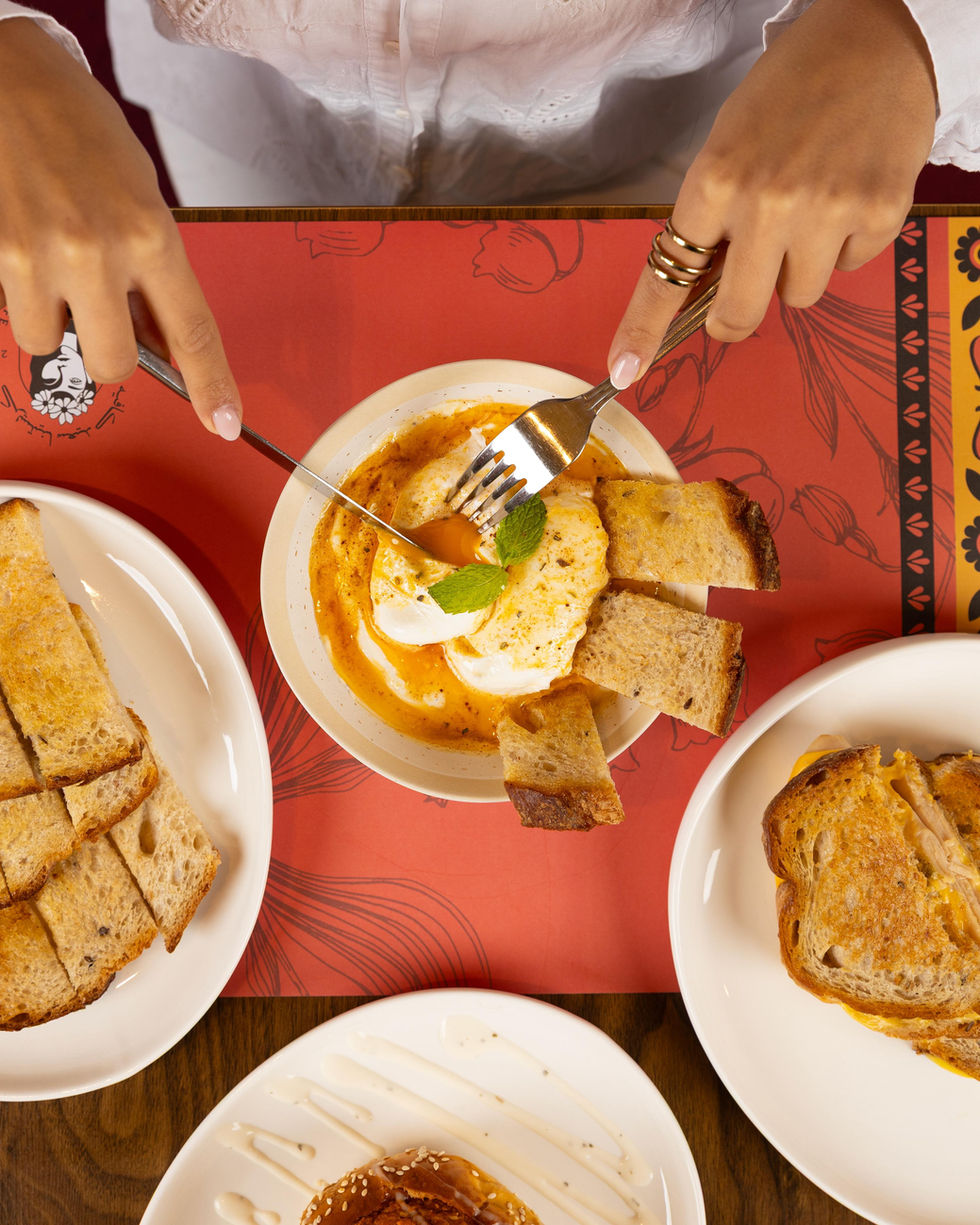 Person eating toast with poached eggs and sauce.