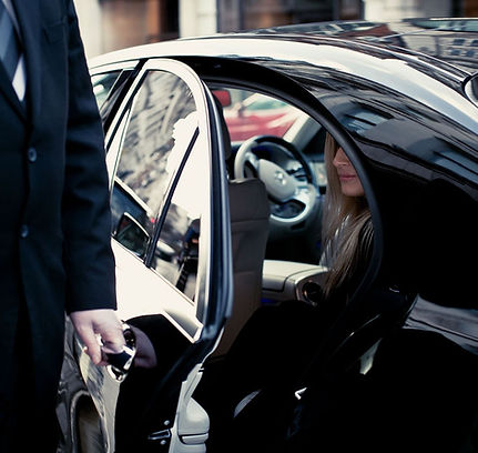 Black car Chauffeur opening door to female passenger