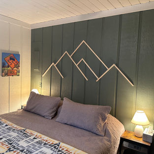 Bed showing a green wall with a wooden mountain design on wall